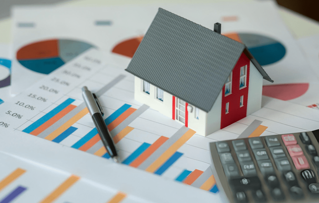 Close-up of a calculator on a desk next to a laptop where someone is working, symbolizing financial planning and real estate cost calculations.