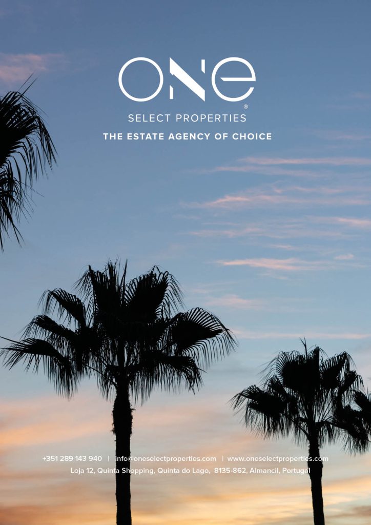 Wide, sunny view of a beautiful Algarve beach, featuring rows of thatched umbrellas and sun loungers, with the ocean waves breaking on the sand.