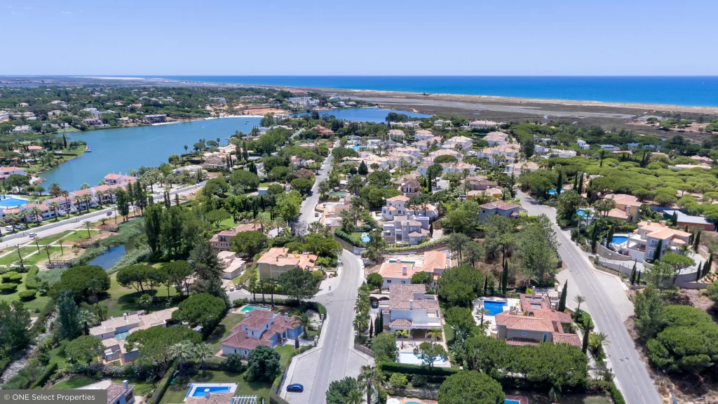 Vista aérea da Encosta do Lago com piscinas de estilo resort, campos de ténis e ambiente residencial.
