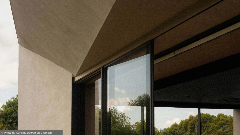 Detalhe arquitetónico minimalista do canto de uma habitação moderna, com janela em vidro e parede de linhas elegantes, evidenciando elementos de design de luxo contemporâneo.